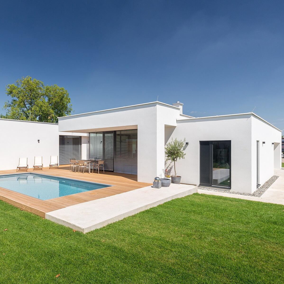 Einfamilienhaus Siegendorf – Frontansicht weißes Einfamilienhaus mit Flachdach und Garten